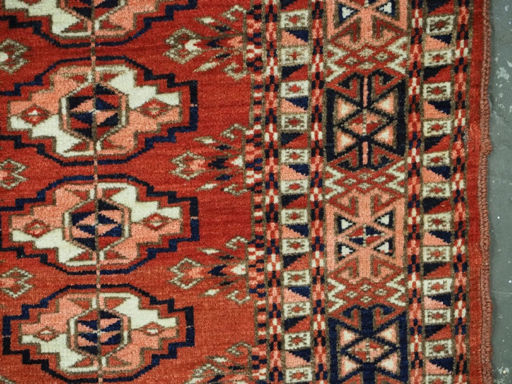 An antique Tekke Turkmen chuval woven textile face featuring thirty repeating octagonal guls on a deep red wool field with geometric borders and a decorated skirt. View IX