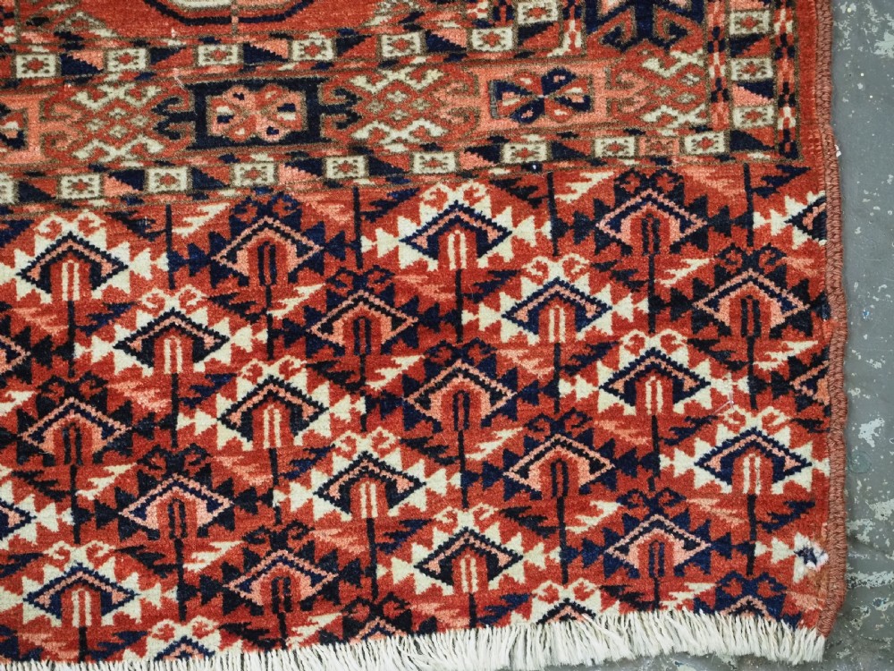 An antique Tekke Turkmen chuval woven textile face featuring thirty repeating octagonal guls on a deep red wool field with geometric borders and a decorated skirt. View X