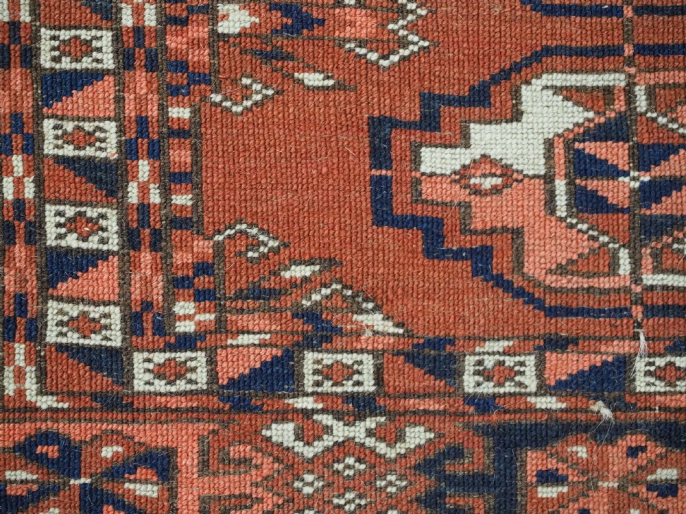 An antique Tekke Turkmen chuval woven textile face featuring thirty repeating octagonal guls on a deep red wool field with geometric borders and a decorated skirt. View XI