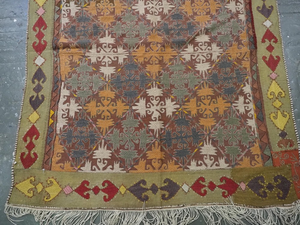 A long rectangular antique Uzbek handwoven wool suzani runner rug with a diamond lattice pattern and geometric border motifs in earth tones. View VI