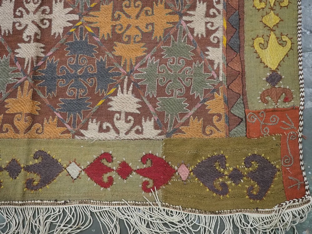 A long rectangular antique Uzbek handwoven wool suzani runner rug with a diamond lattice pattern and geometric border motifs in earth tones. View XI
