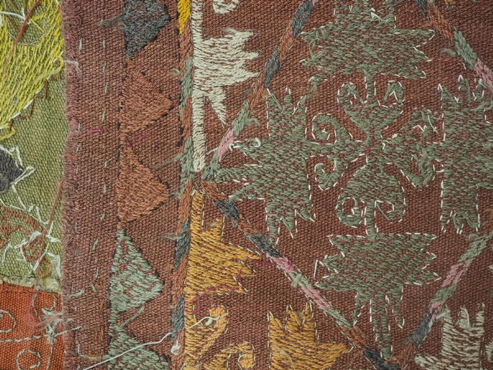 A long rectangular antique Uzbek handwoven wool suzani runner rug with a diamond lattice pattern and geometric border motifs in earth tones. View XII