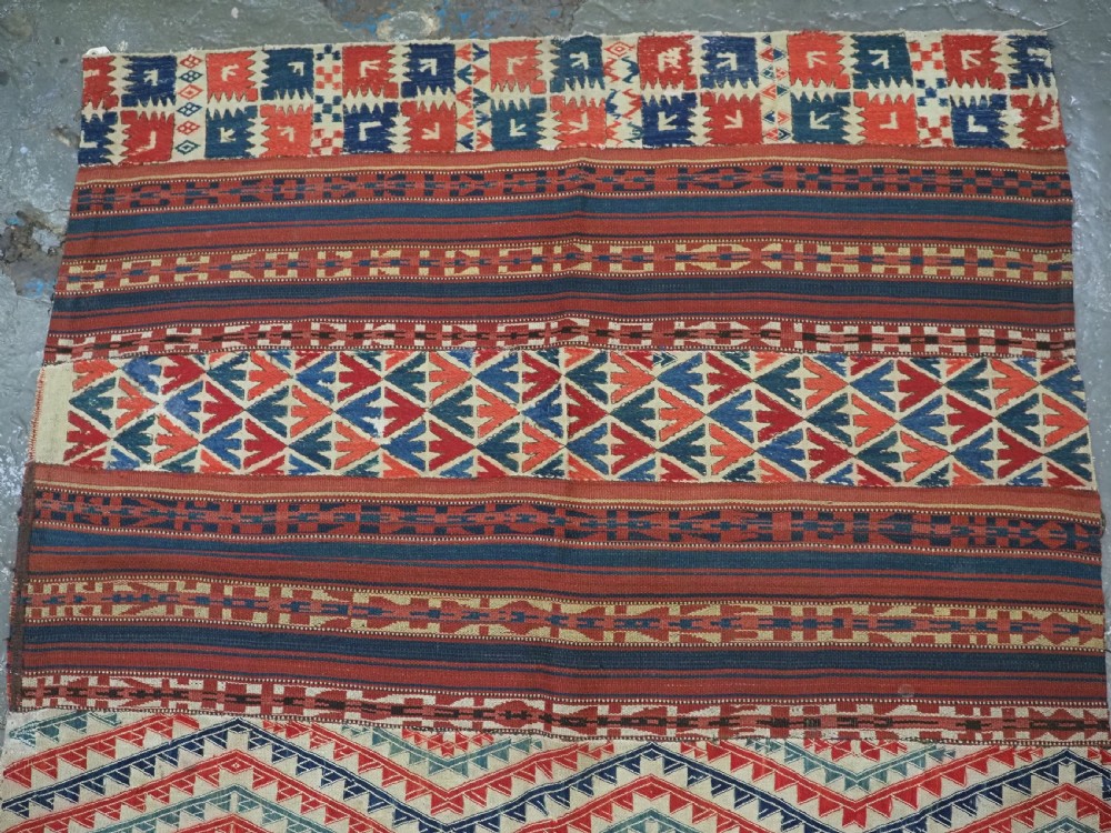 An antique central Asian kilim rug composed of thirteen vertical strips showing geometric diamond and stripe patterns in red, navy blue, and cream. View II