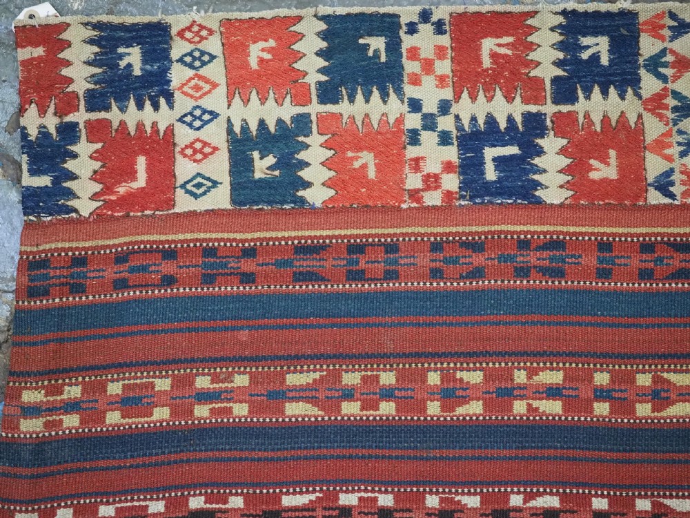 An antique central Asian kilim rug composed of thirteen vertical strips showing geometric diamond and stripe patterns in red, navy blue, and cream. View VI