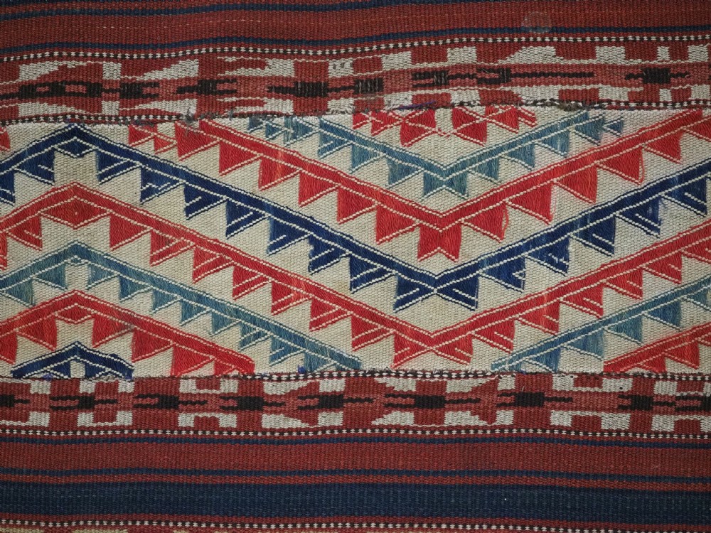 An antique central Asian kilim rug composed of thirteen vertical strips showing geometric diamond and stripe patterns in red, navy blue, and cream. View IX