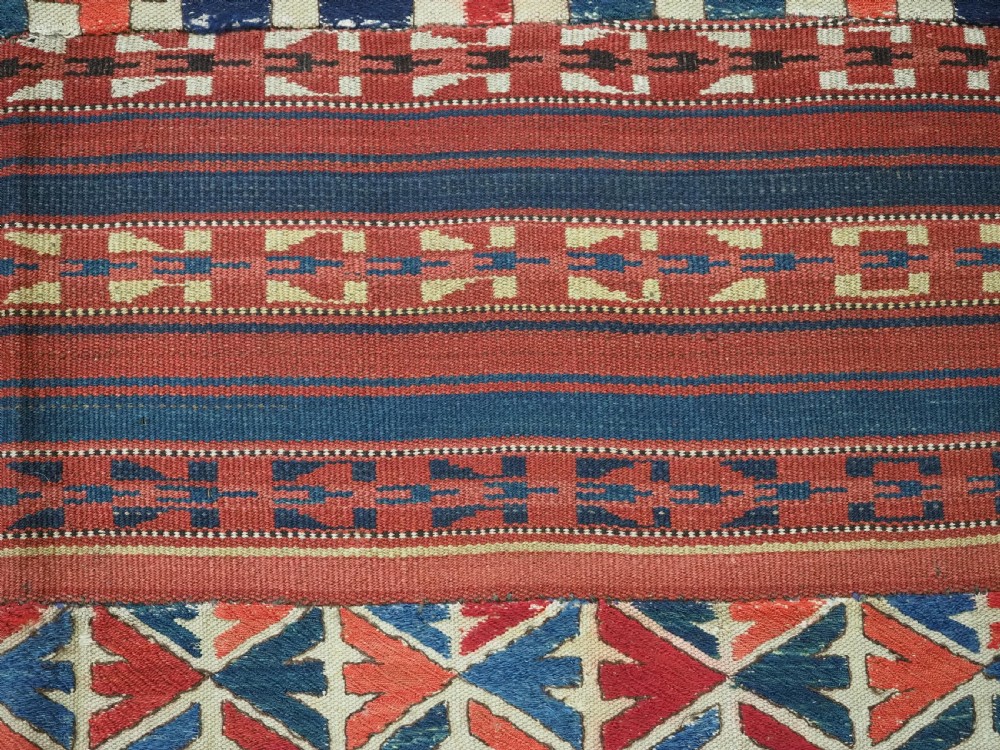 An antique central Asian kilim rug composed of thirteen vertical strips showing geometric diamond and stripe patterns in red, navy blue, and cream. View XI
