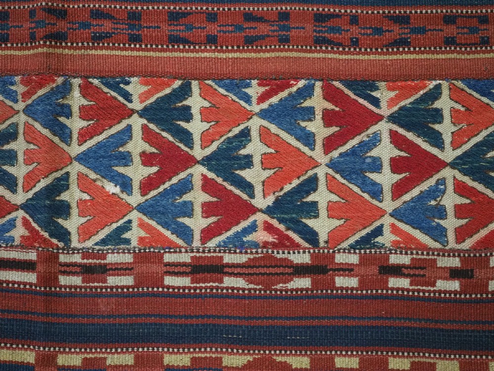 An antique central Asian kilim rug composed of thirteen vertical strips showing geometric diamond and stripe patterns in red, navy blue, and cream. View XII