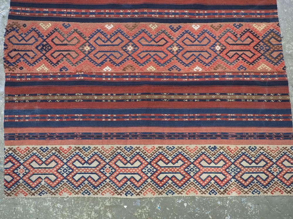An antique handwoven Uzbek kilim panel constructed from four joined strips featuring terracotta red, indigo blue, and ivory geometric patterns. View III