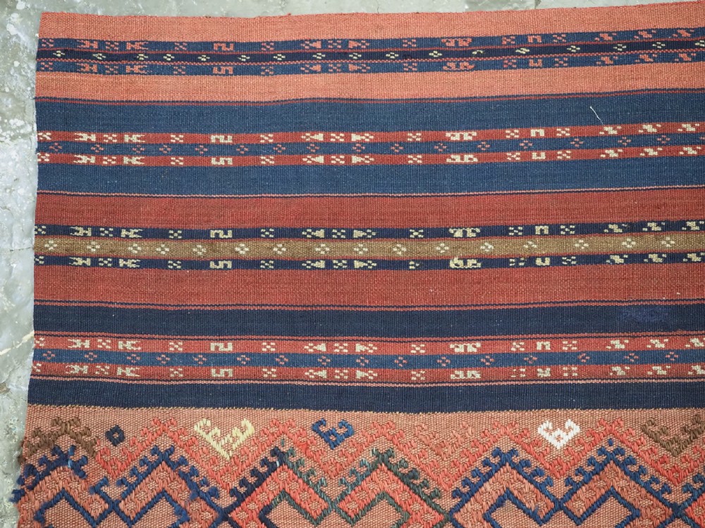An antique handwoven Uzbek kilim panel constructed from four joined strips featuring terracotta red, indigo blue, and ivory geometric patterns. View IV