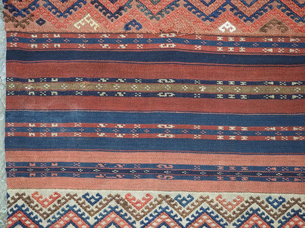 An antique handwoven Uzbek kilim panel constructed from four joined strips featuring terracotta red, indigo blue, and ivory geometric patterns. View VII