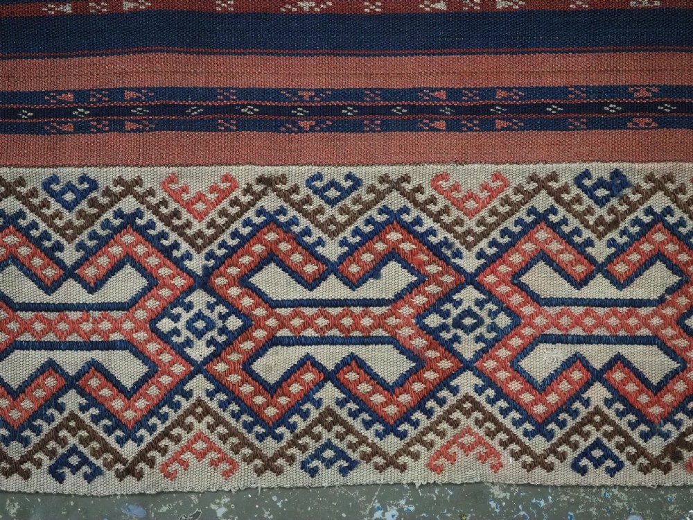 An antique handwoven Uzbek kilim panel constructed from four joined strips featuring terracotta red, indigo blue, and ivory geometric patterns. View IX