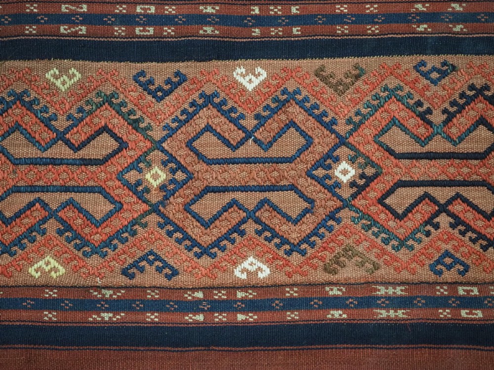 An antique handwoven Uzbek kilim panel constructed from four joined strips featuring terracotta red, indigo blue, and ivory geometric patterns. View X