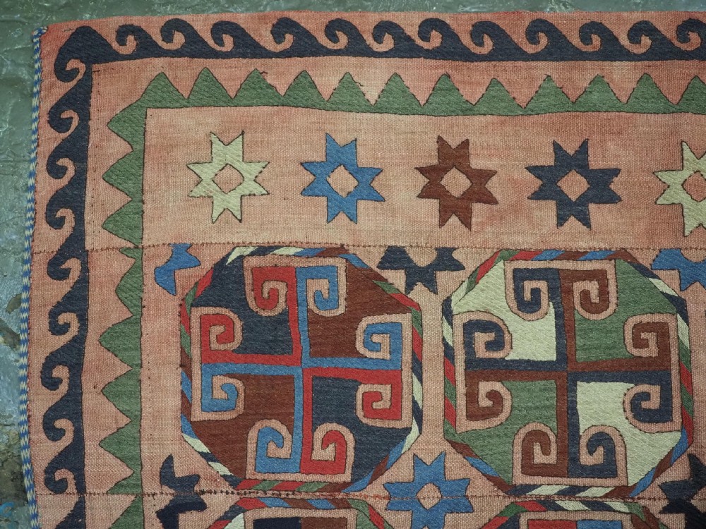 An antique flatweave rug composed of nine stitched vertical strips featuring repeating octagonal geometric motifs and star borders on a faded red background. View VII