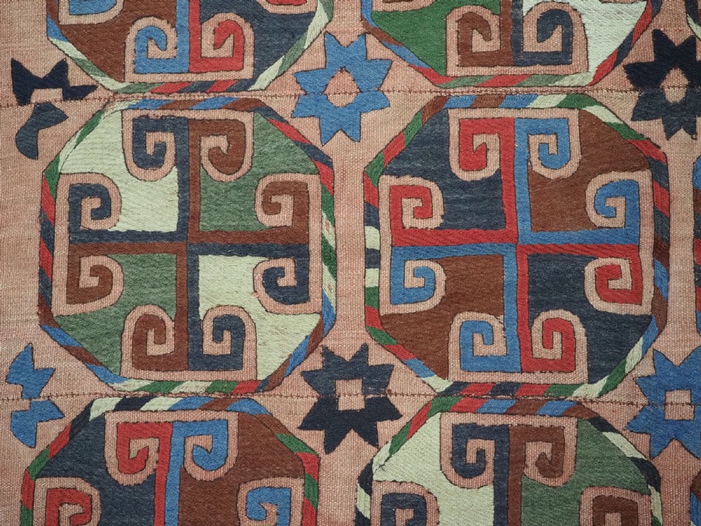 An antique flatweave rug composed of nine stitched vertical strips featuring repeating octagonal geometric motifs and star borders on a faded red background. View VIII