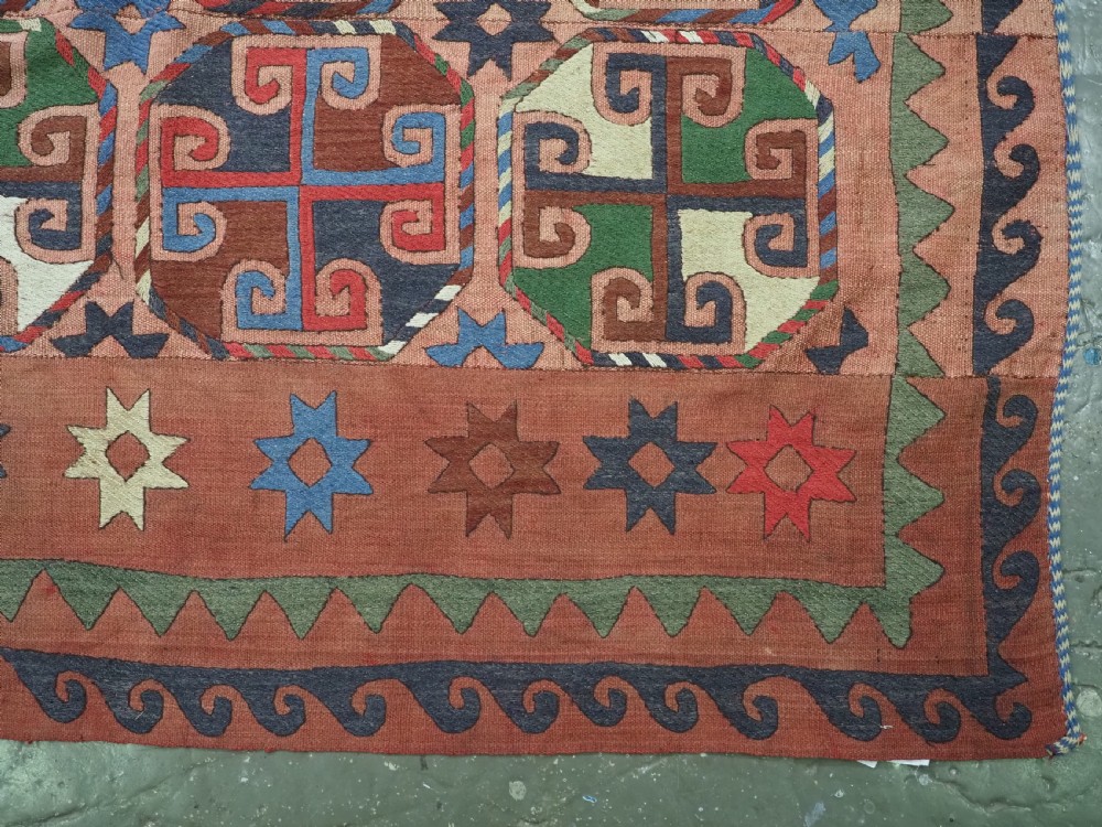 An antique flatweave rug composed of nine stitched vertical strips featuring repeating octagonal geometric motifs and star borders on a faded red background. View XI