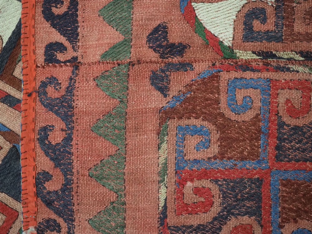 An antique flatweave rug composed of nine stitched vertical strips featuring repeating octagonal geometric motifs and star borders on a faded red background. View XII