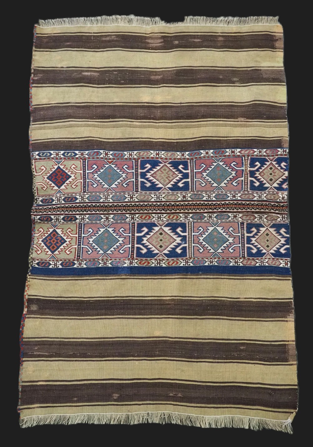 A flatwoven wool Caucasian kilim rug featuring horizontal brown and cream stripes alongside geometric diamond panels in indigo blue, terracotta, and green.