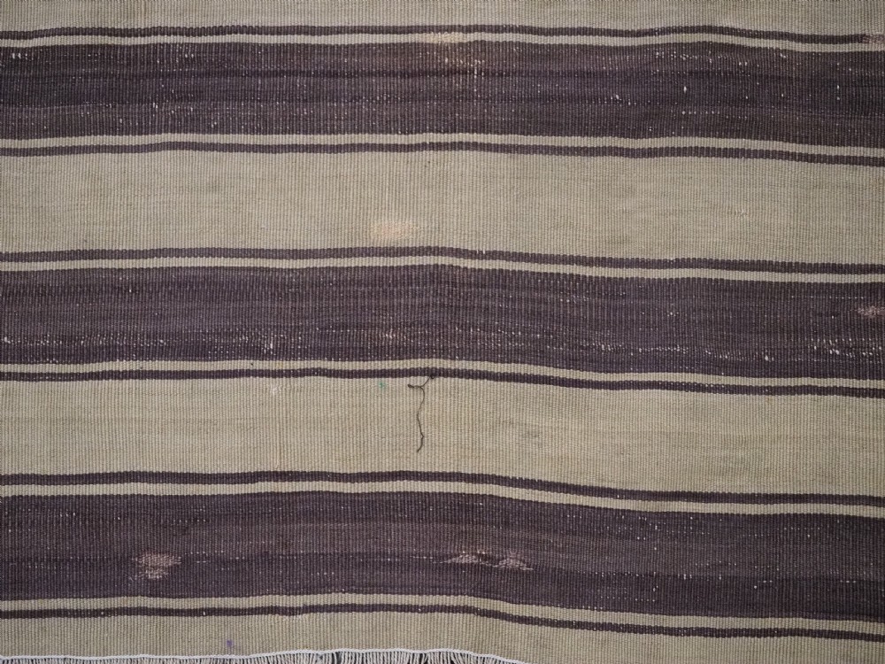 A flatwoven wool Caucasian kilim rug featuring horizontal brown and cream stripes alongside geometric diamond panels in indigo blue, terracotta, and green. View VIII