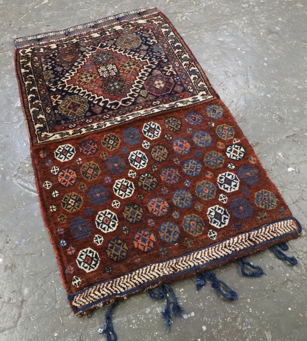 A late 19th-century South Persian hand-woven wool double saddle bag featuring geometric medallions, repeated guls, and stepped diamond patterns in shades of deep red, indigo blue, and ivory. View II