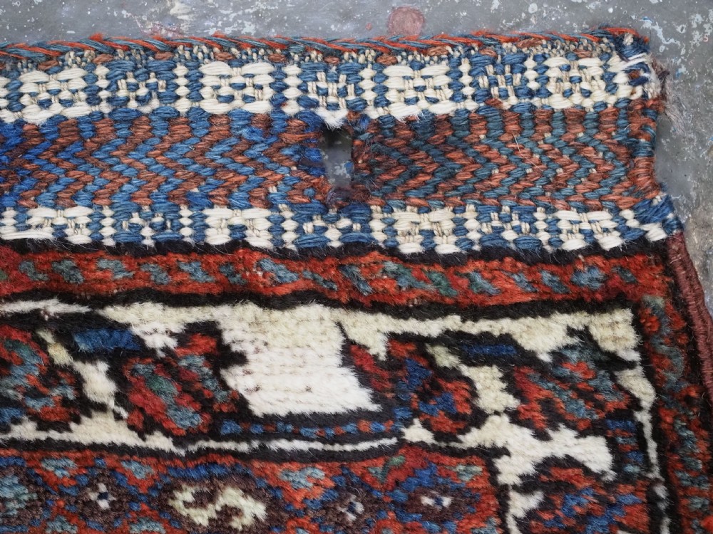 A late 19th-century South Persian hand-woven wool double saddle bag featuring geometric medallions, repeated guls, and stepped diamond patterns in shades of deep red, indigo blue, and ivory. View VII