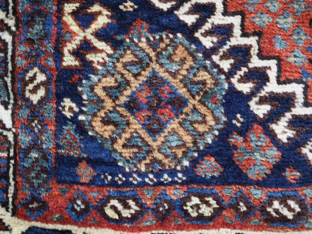 A late 19th-century South Persian hand-woven wool double saddle bag featuring geometric medallions, repeated guls, and stepped diamond patterns in shades of deep red, indigo blue, and ivory. View VIII