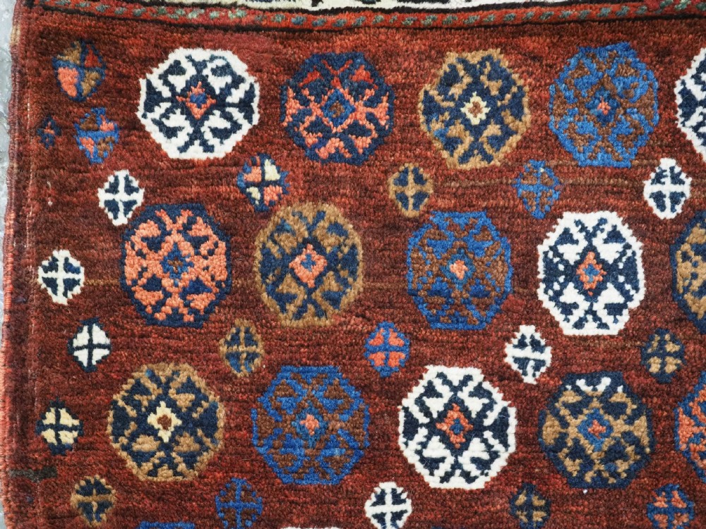 A late 19th-century South Persian hand-woven wool double saddle bag featuring geometric medallions, repeated guls, and stepped diamond patterns in shades of deep red, indigo blue, and ivory. View X