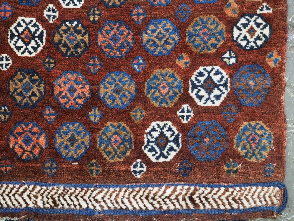 A late 19th-century South Persian hand-woven wool double saddle bag featuring geometric medallions, repeated guls, and stepped diamond patterns in shades of deep red, indigo blue, and ivory. View XII