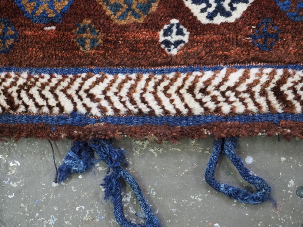 A late 19th-century South Persian hand-woven wool double saddle bag featuring geometric medallions, repeated guls, and stepped diamond patterns in shades of deep red, indigo blue, and ivory. View XIII