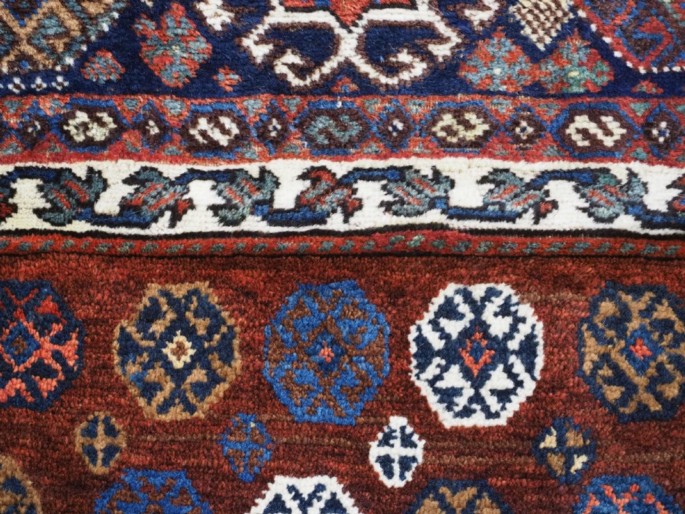 A late 19th-century South Persian hand-woven wool double saddle bag featuring geometric medallions, repeated guls, and stepped diamond patterns in shades of deep red, indigo blue, and ivory. View XIV