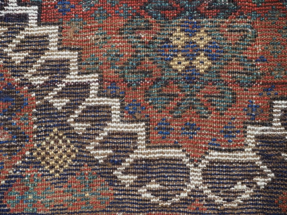 A late 19th-century South Persian hand-woven wool double saddle bag featuring geometric medallions, repeated guls, and stepped diamond patterns in shades of deep red, indigo blue, and ivory. View XVI