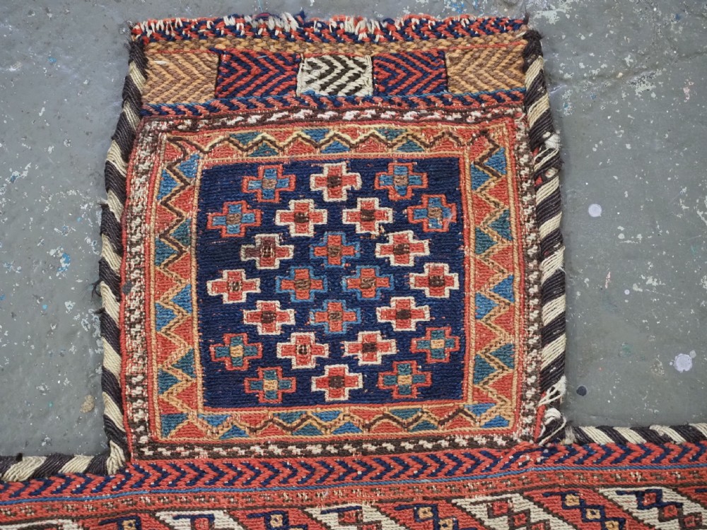 An antique Afshar tribal salt bag featuring a bottleneck neck and wide body woven in dark blue, rust red, and white geometric Soumak patterns. View III