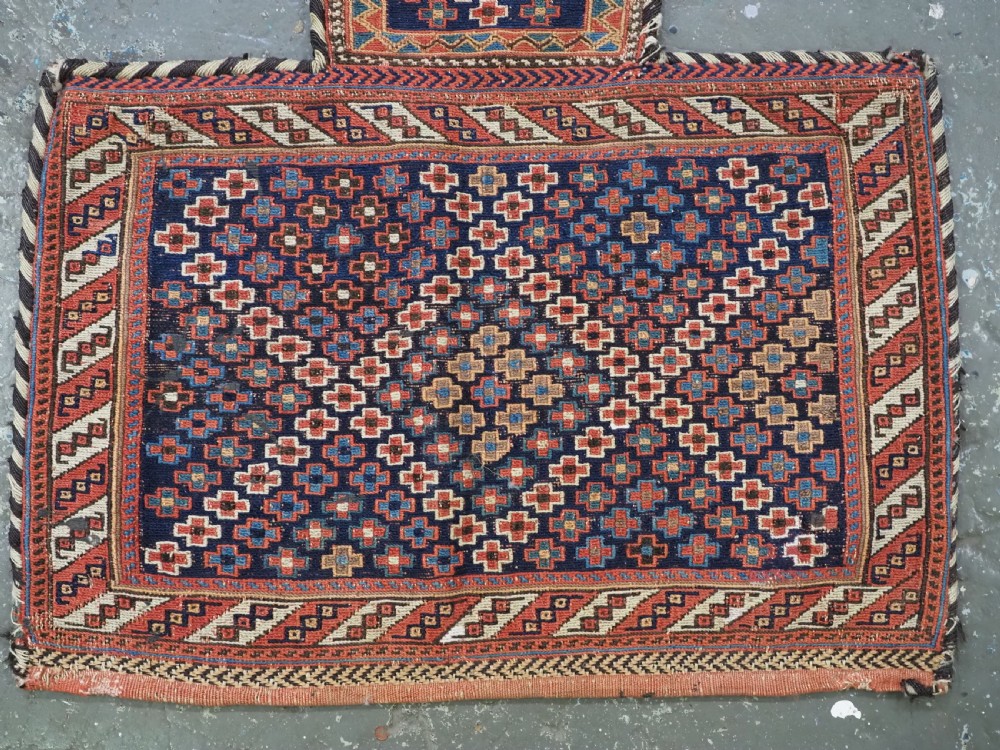 An antique Afshar tribal salt bag featuring a bottleneck neck and wide body woven in dark blue, rust red, and white geometric Soumak patterns. View IV