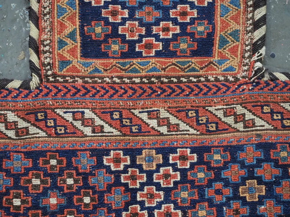 An antique Afshar tribal salt bag featuring a bottleneck neck and wide body woven in dark blue, rust red, and white geometric Soumak patterns. View V