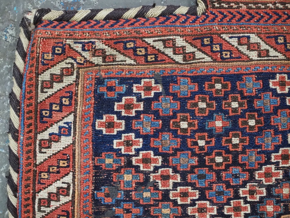 An antique Afshar tribal salt bag featuring a bottleneck neck and wide body woven in dark blue, rust red, and white geometric Soumak patterns. View VI