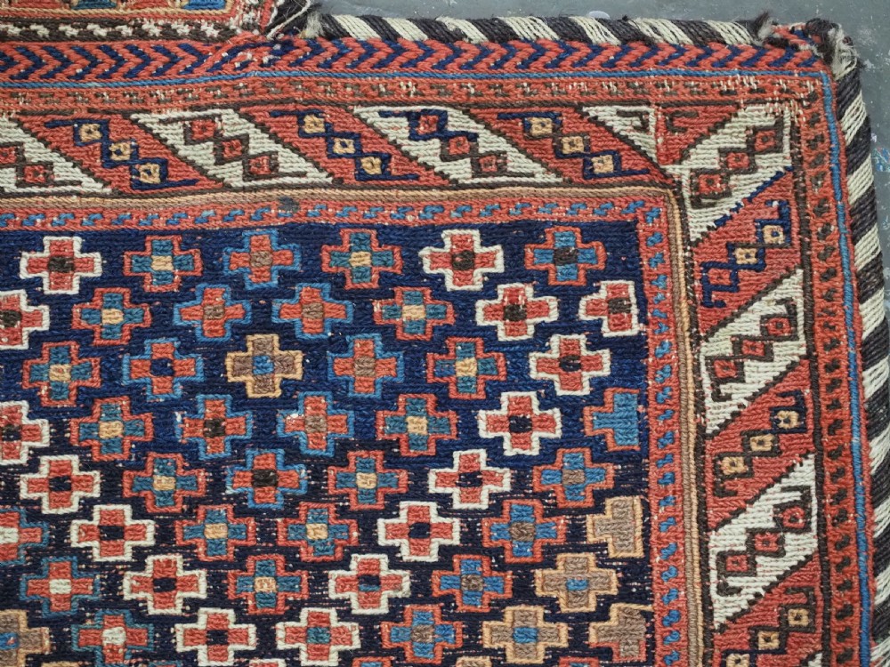An antique Afshar tribal salt bag featuring a bottleneck neck and wide body woven in dark blue, rust red, and white geometric Soumak patterns. View IX