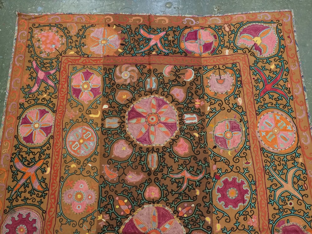 An antique Uzbek Shahrisabz region suzani textile with pink and orange silk embroidered floral medallions on a brown cotton field. View II
