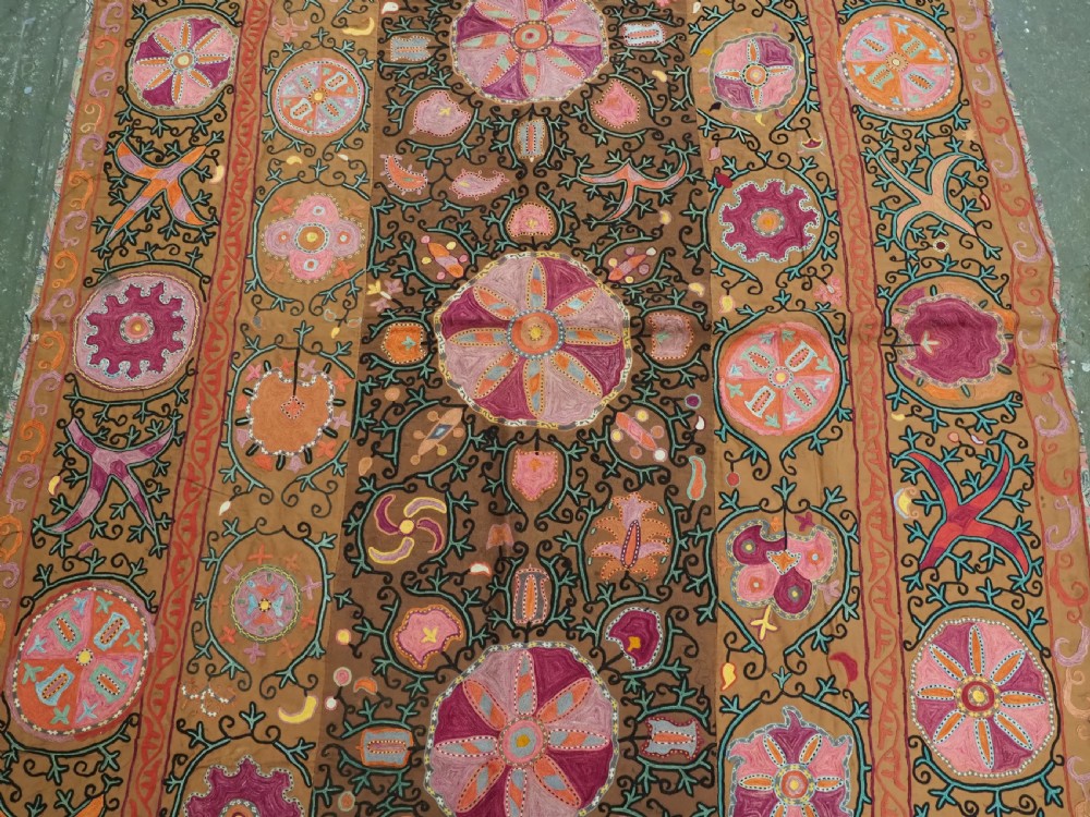 An antique Uzbek Shahrisabz region suzani textile with pink and orange silk embroidered floral medallions on a brown cotton field. View III
