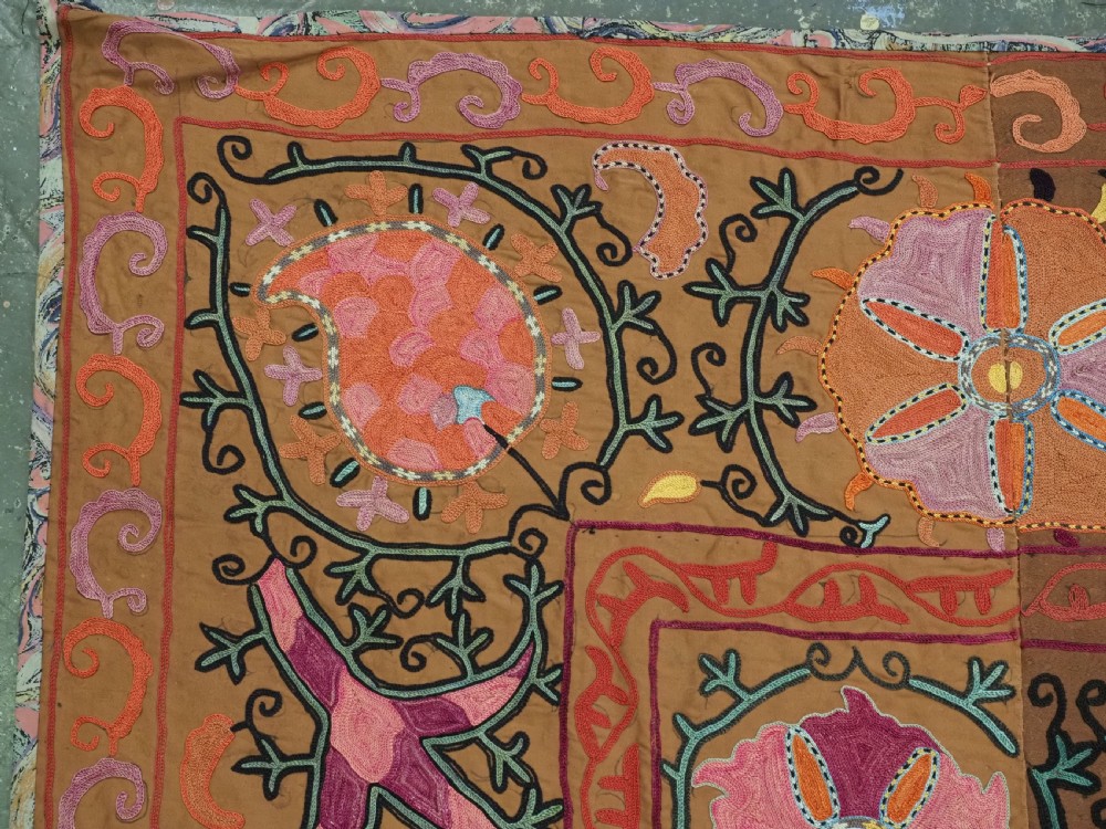 An antique Uzbek Shahrisabz region suzani textile with pink and orange silk embroidered floral medallions on a brown cotton field. View V