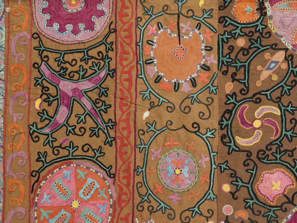 An antique Uzbek Shahrisabz region suzani textile with pink and orange silk embroidered floral medallions on a brown cotton field. View VI