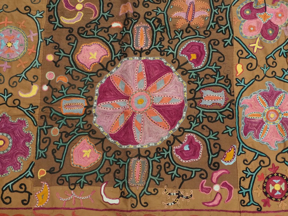 An antique Uzbek Shahrisabz region suzani textile with pink and orange silk embroidered floral medallions on a brown cotton field. View X