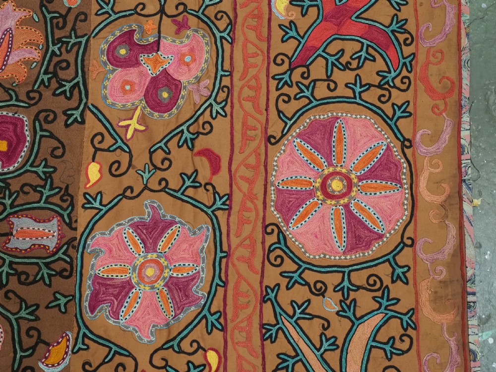 An antique Uzbek Shahrisabz region suzani textile with pink and orange silk embroidered floral medallions on a brown cotton field. View XI