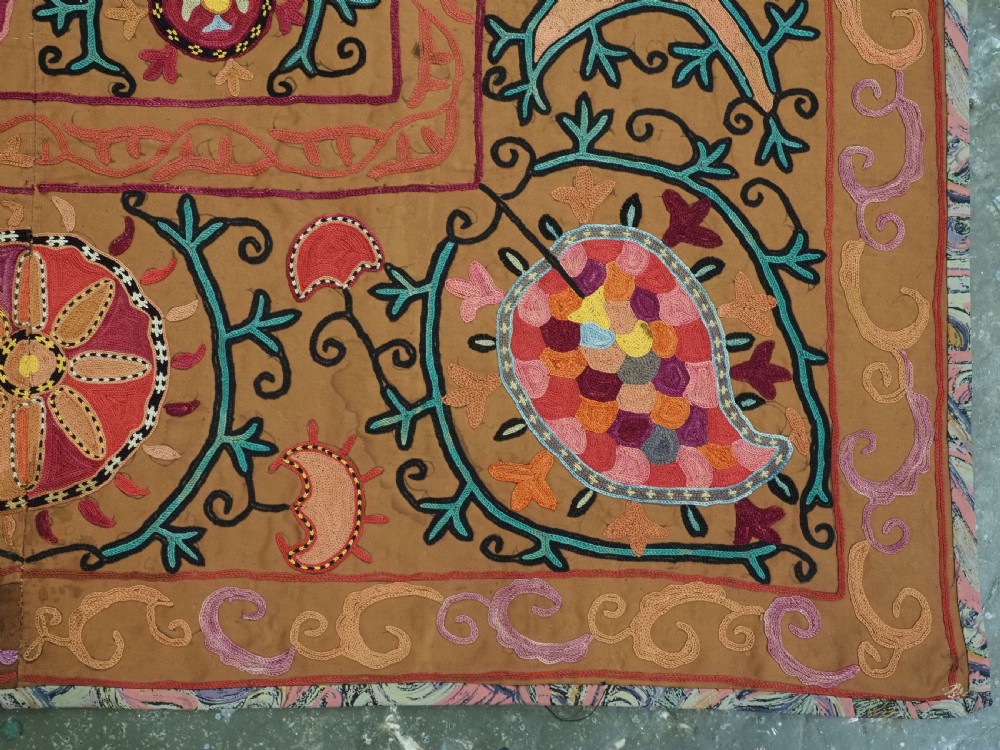 An antique Uzbek Shahrisabz region suzani textile with pink and orange silk embroidered floral medallions on a brown cotton field. View XII
