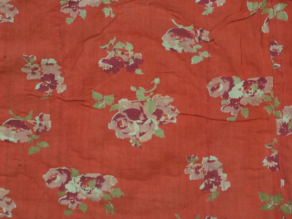 A rectangular antique crimson red textile featuring intricate silk embroidery with solar medallion motifs, floral scrolls, and geometric borders in yellow, blue, and pink. View X
