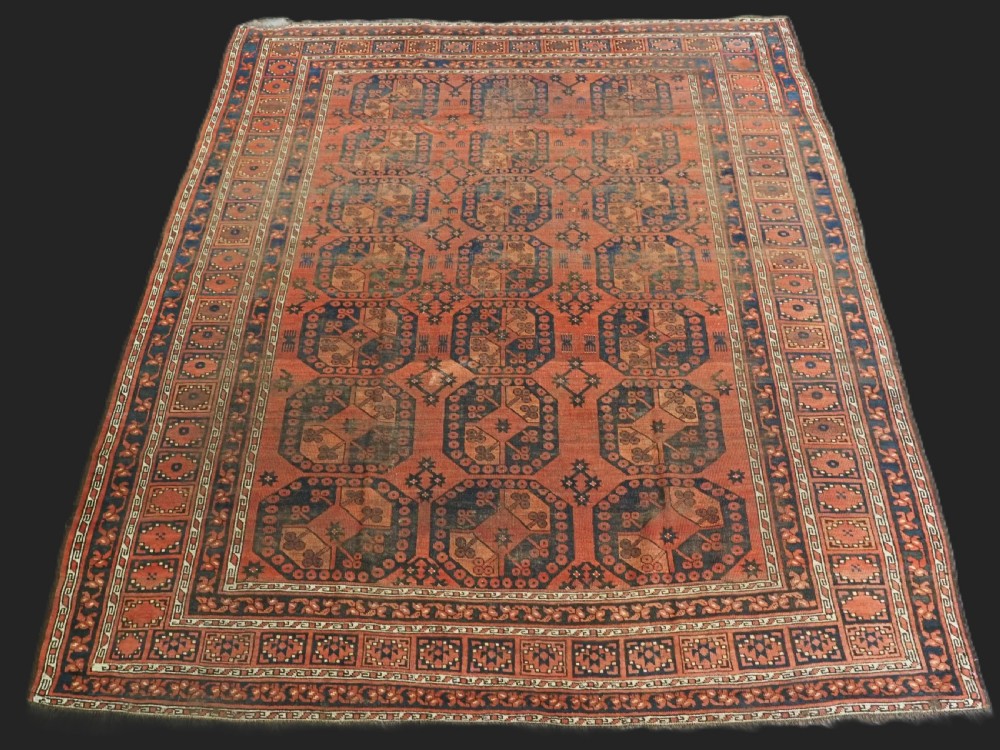 An antique Ersari Turkmen hand-knotted wool carpet displaying repeated octagonal gol motifs on a terracotta field with geometric borders.