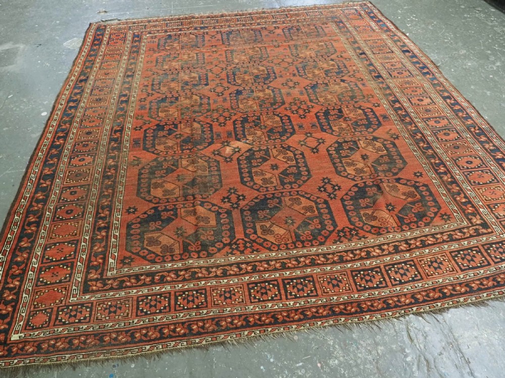 An antique Ersari Turkmen hand-knotted wool carpet displaying repeated octagonal gol motifs on a terracotta field with geometric borders. View II