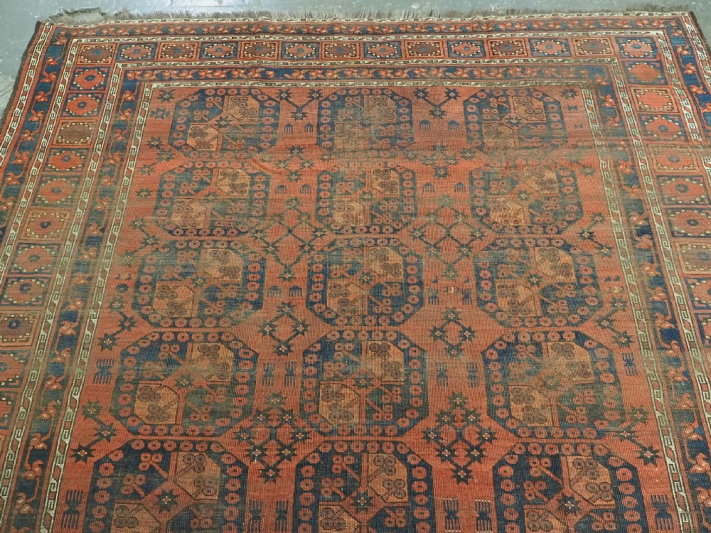 An antique Ersari Turkmen hand-knotted wool carpet displaying repeated octagonal gol motifs on a terracotta field with geometric borders. View III