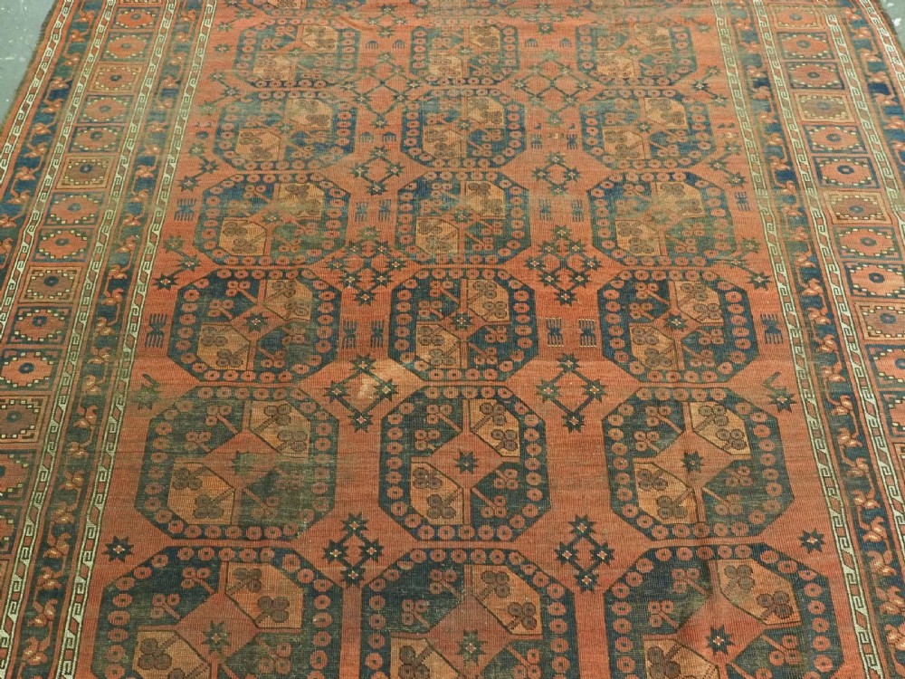 An antique Ersari Turkmen hand-knotted wool carpet displaying repeated octagonal gol motifs on a terracotta field with geometric borders. View IV