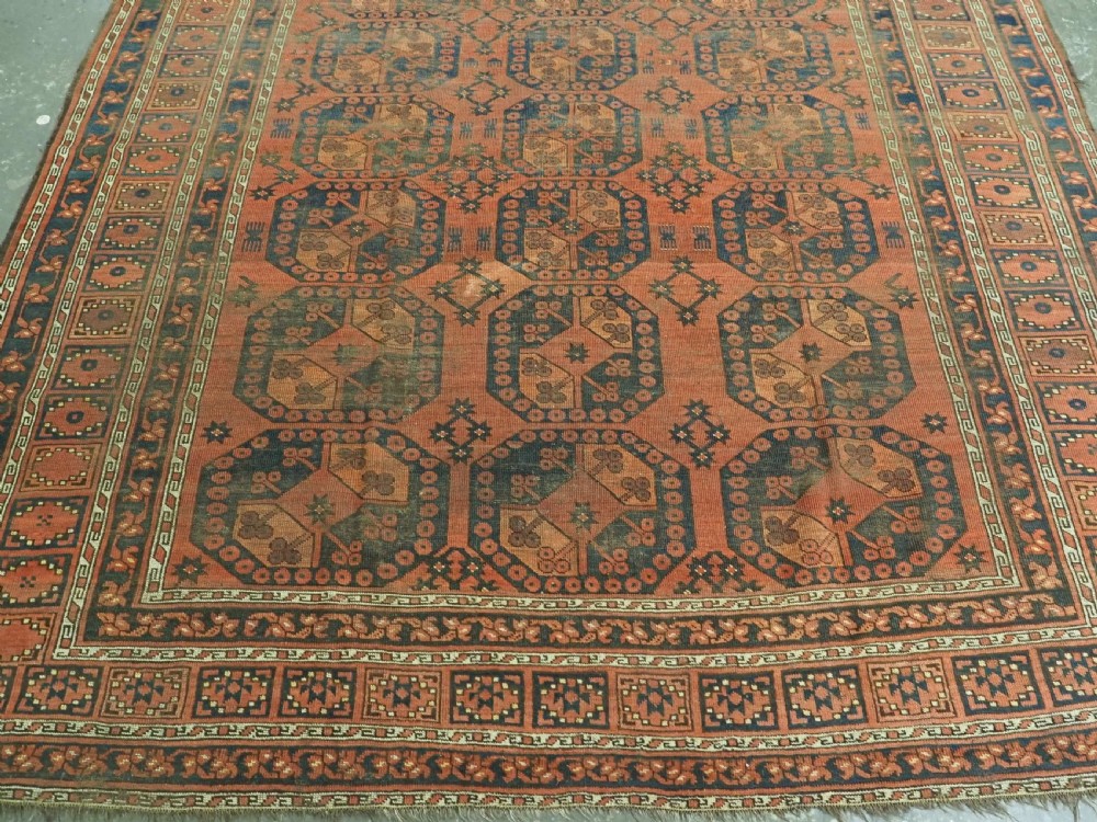 An antique Ersari Turkmen hand-knotted wool carpet displaying repeated octagonal gol motifs on a terracotta field with geometric borders. View V