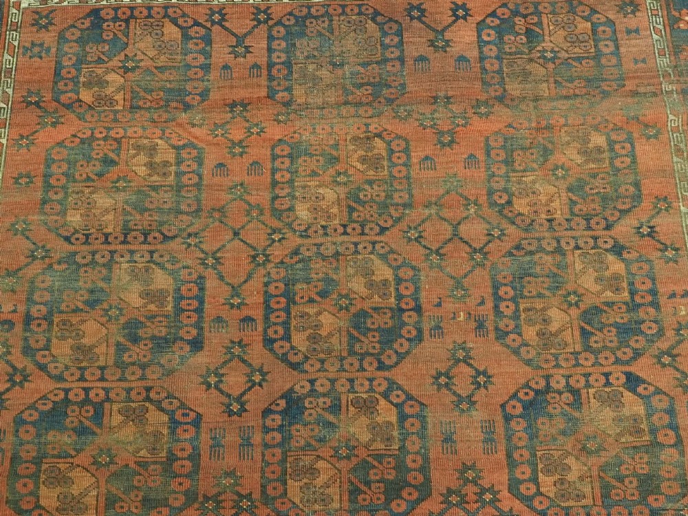 An antique Ersari Turkmen hand-knotted wool carpet displaying repeated octagonal gol motifs on a terracotta field with geometric borders. View VIII