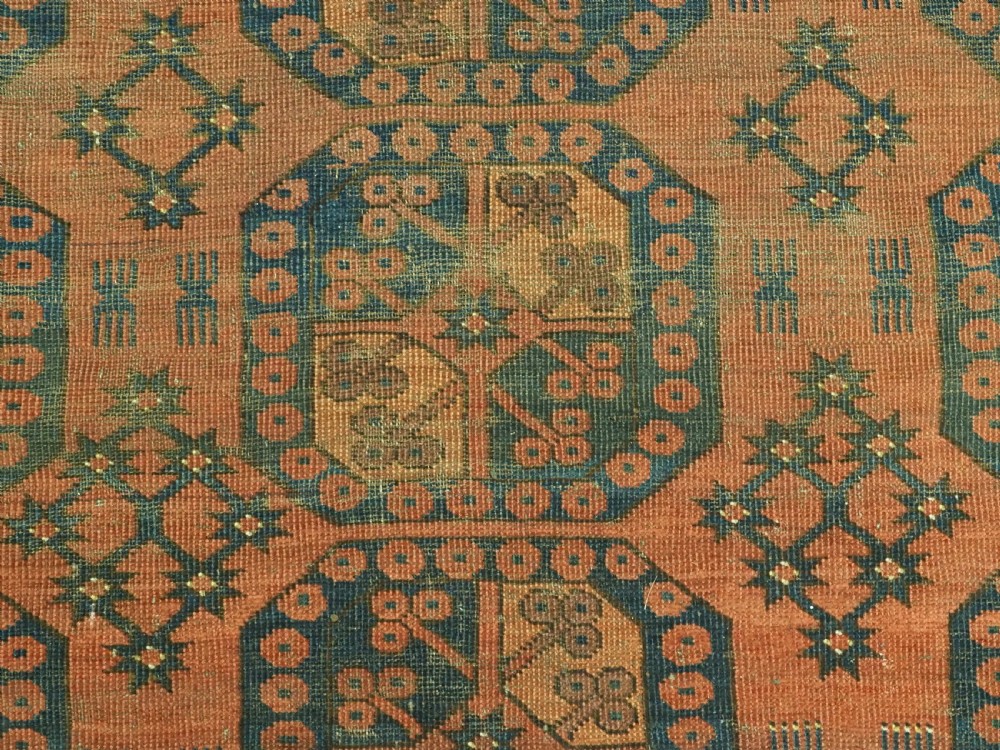 An antique Ersari Turkmen hand-knotted wool carpet displaying repeated octagonal gol motifs on a terracotta field with geometric borders. View IX